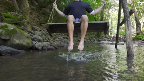 Swinging-on-a-swing-over-the-stream.-Slow-Motion.